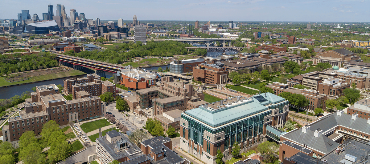 Aerial view of both UMN Twin Cities Campuses with downtown Minneapolis on the horizon 