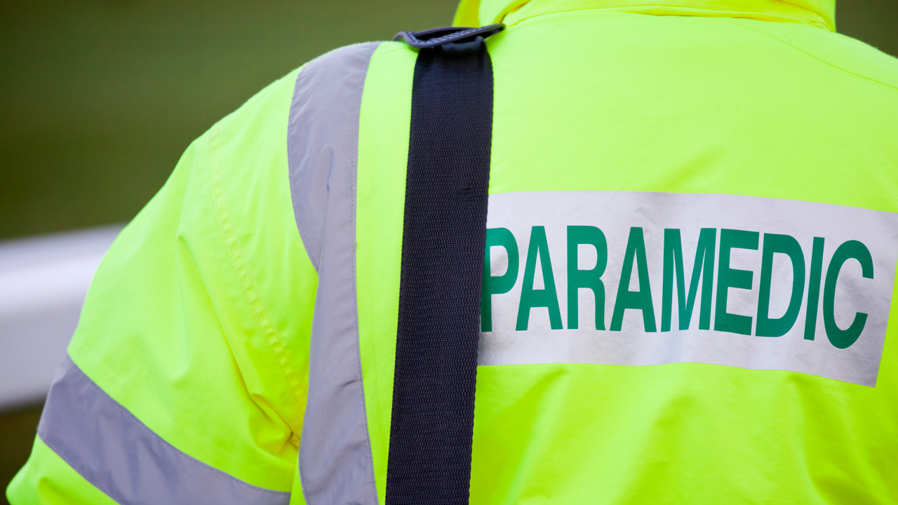 A person wearing a yellow jacket with the word "paramedic" across the back