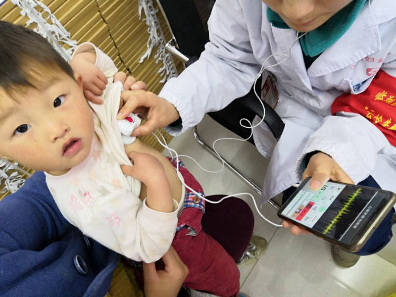 Doctor using tech to check a child's heart rhythm.