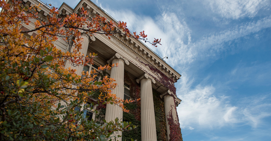 low angle of the front of Johnston Hall with the foliage turning autumnal colors