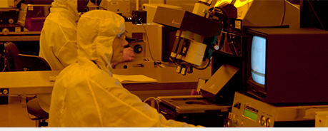 Researchers in protective suits in a dimly lit laboratory, observing monitors and equipment