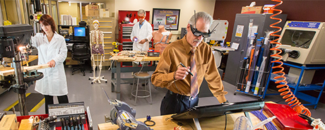 Several researchers in a workshop laboratory, in PPE