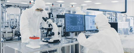 Two researchers in PPE working at a lab table and computer