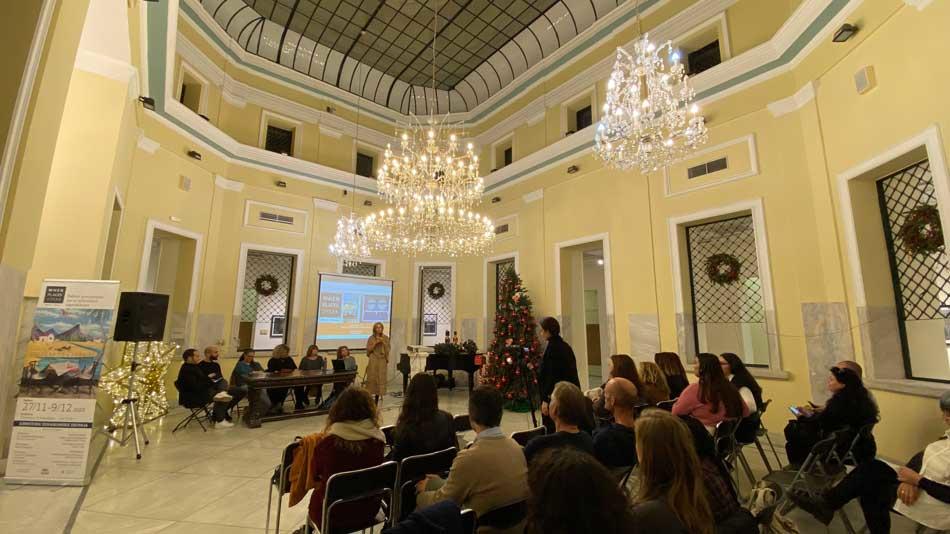 Large room with chandelier hosting a panel and audience