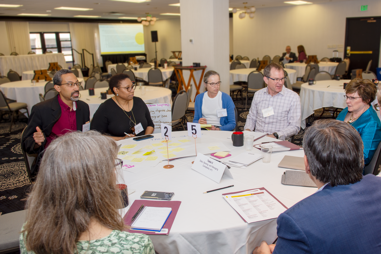 Group sits at a table, discussion ensues