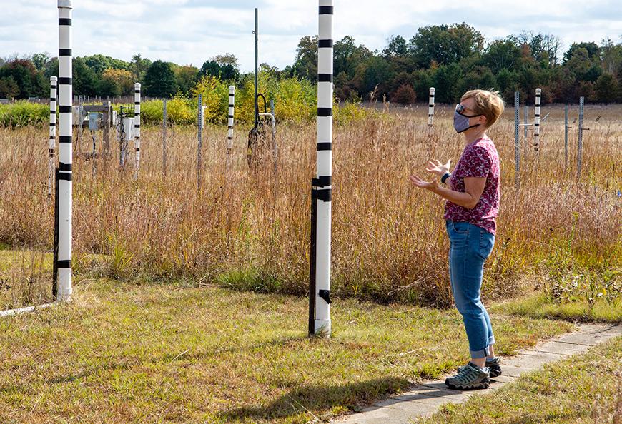 Woman standing outside next to large PVC pipes and plants