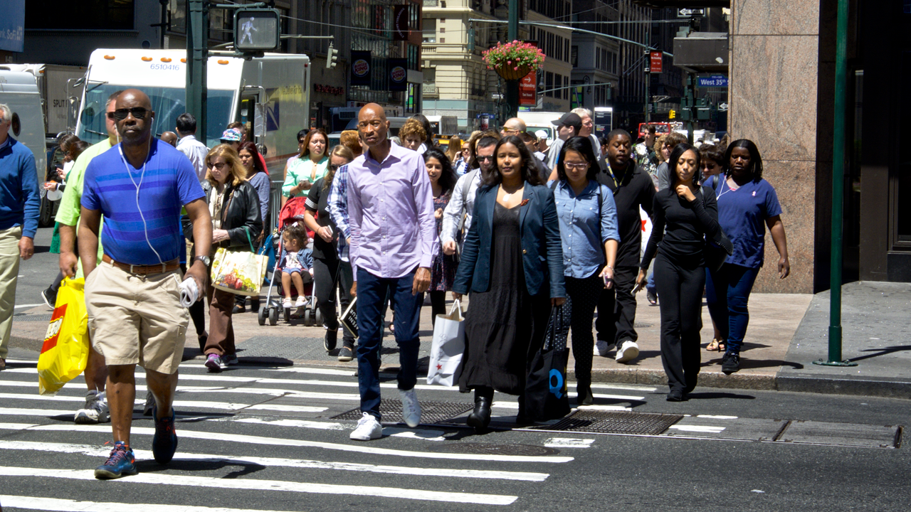 Crowd of people cross a city street