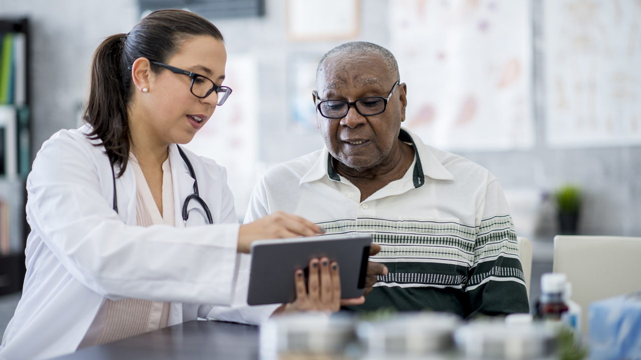 Doctor talks with patient while looking at a tablet