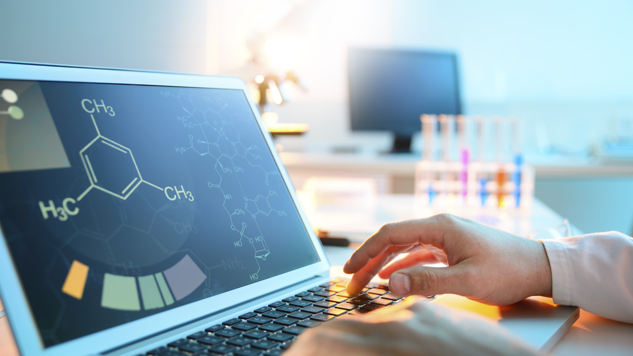 Scientist works on laptop showing molecular structure