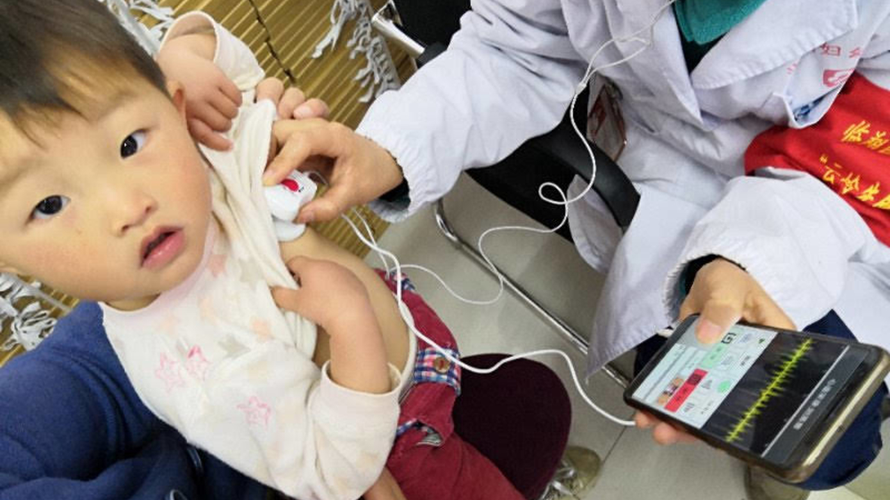 Doctor using tech to check a child's heart rhythm.