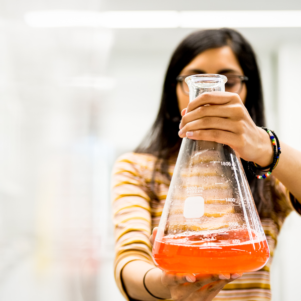 Student holding Erlenmeyer flask in laboratory